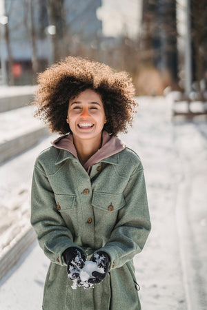 Younger woman smiling hard while wearing Noz reef safe sunscreen in the color orange. 